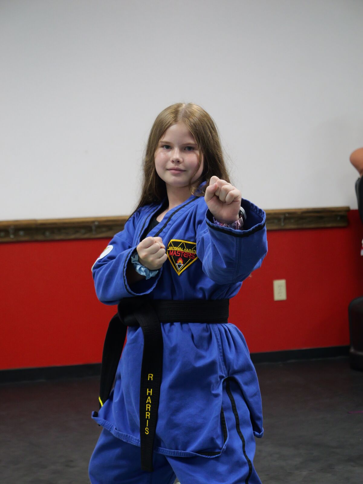 Youth student in a blue uniform throwing a high kick in class