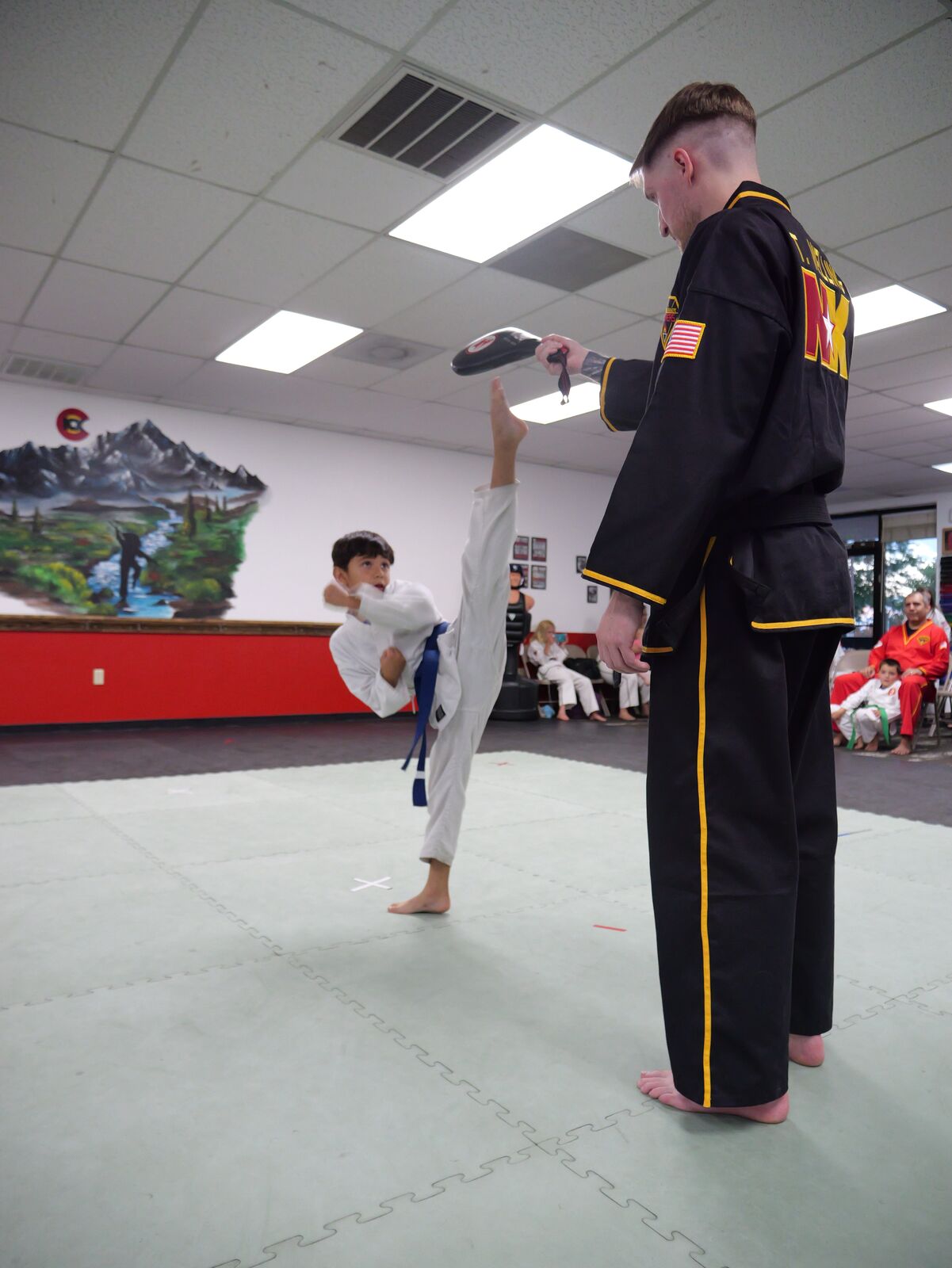 Young child in a white uniform holding a fighting stance during a beginner karate class